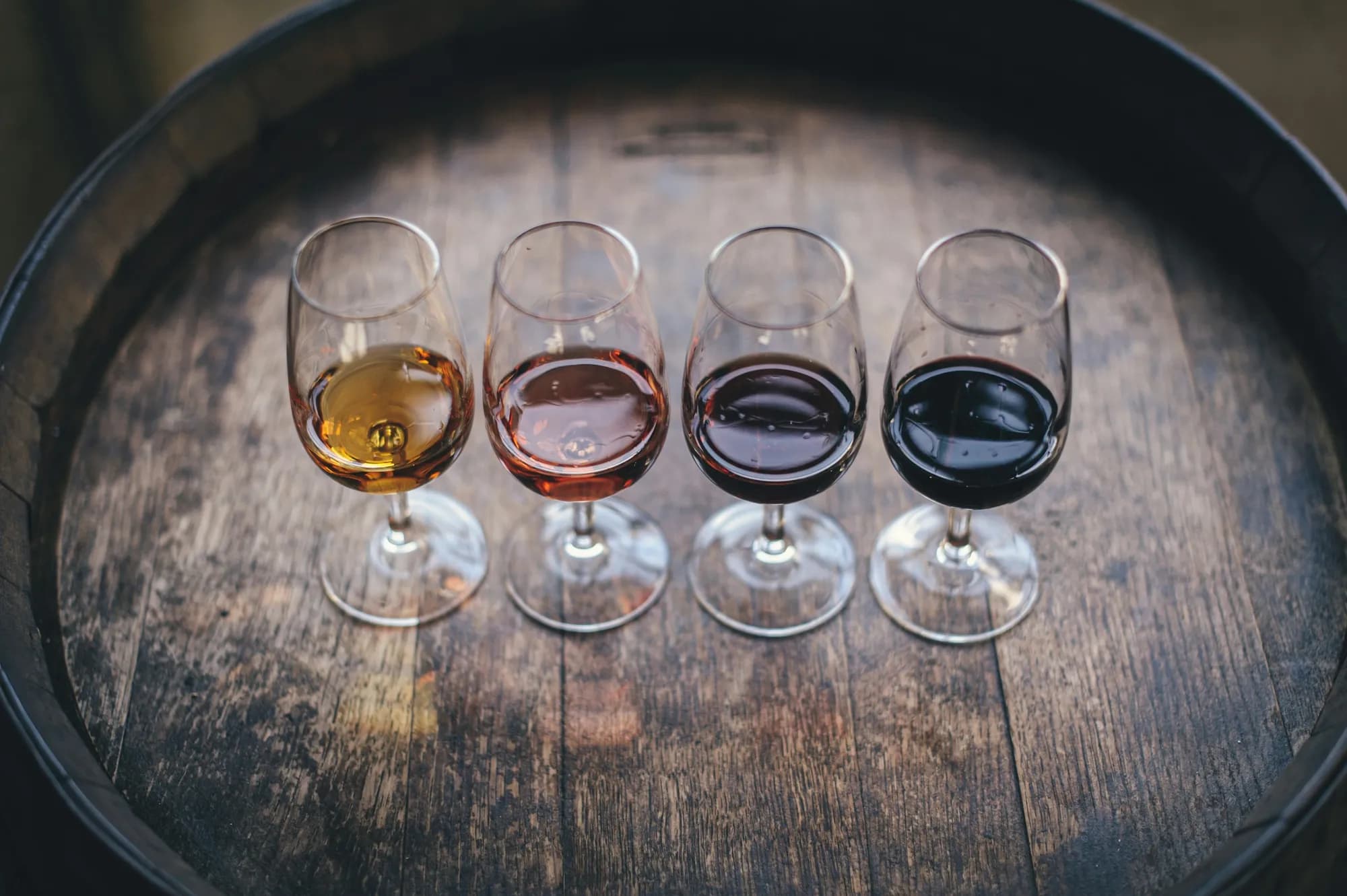 Four glasses of wine in a row, from pale white to deep red